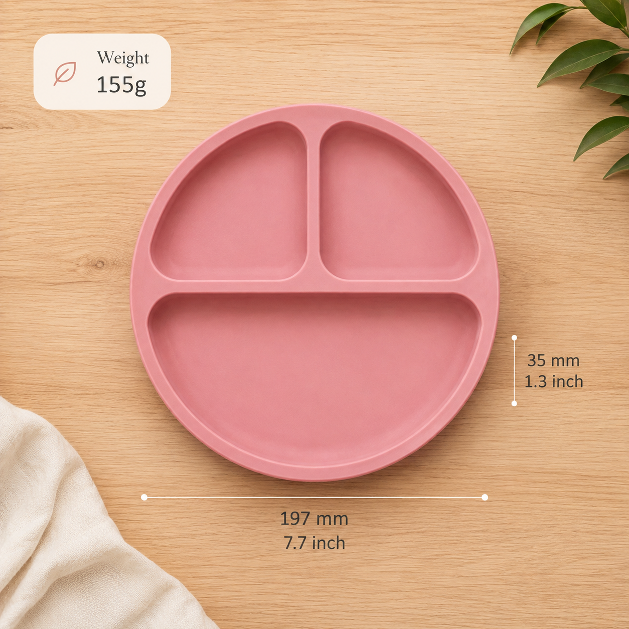 A pink silicone divided plate shown on a light wood surface with measurement callouts indicating 197 mm in diameter and 35 mm height, plus a small weight label reading 155g.