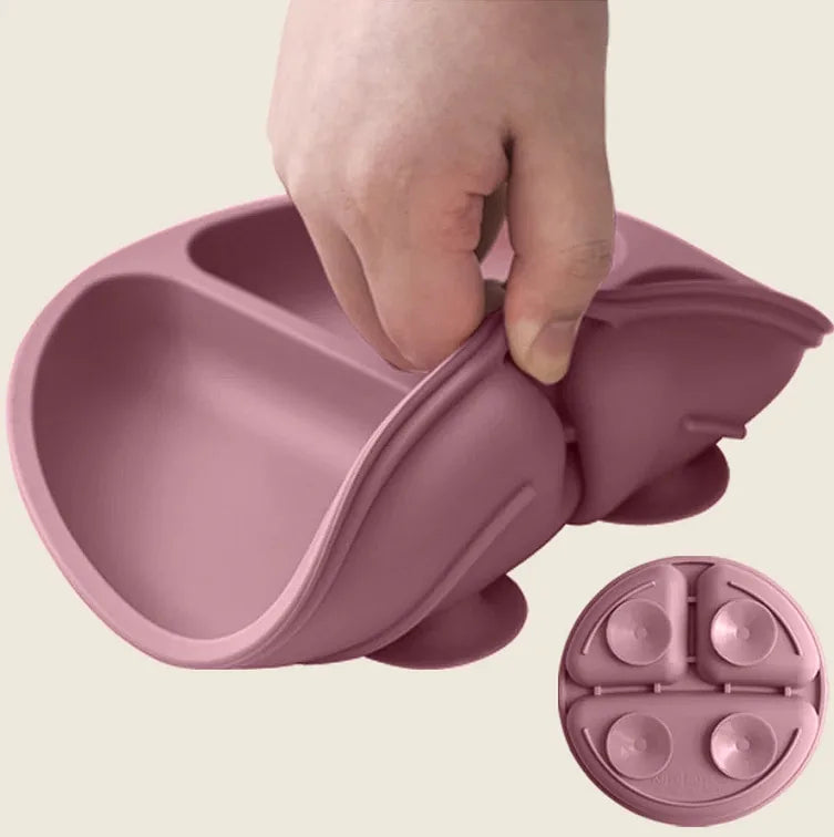 A hand demonstrates the flexibility of a flexible silicone baby feeding bowl in a dusty rose pink color, with a small inset showing the suction cup base detail.